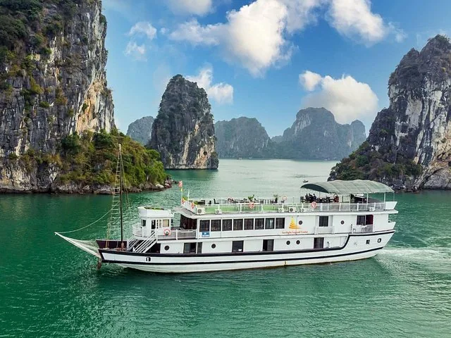 White cruise boat sailing in Halong Bay among limestone karst islands