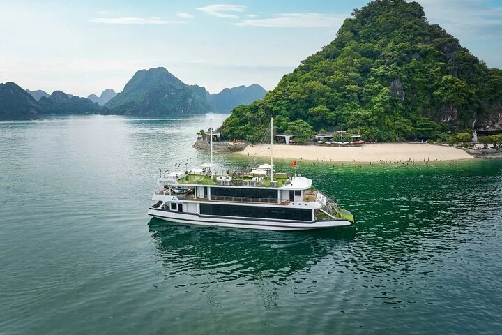Modern cruise ship parked in the sea next to an island with a beach