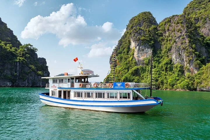 Dragon King cruise ship sailing past limestone formations in Halong Bay