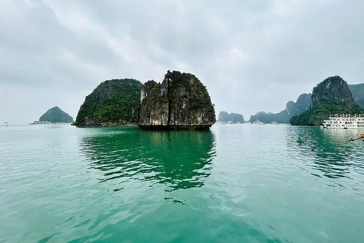 Lush limestone karst formations rising from the green waters of a calm bay