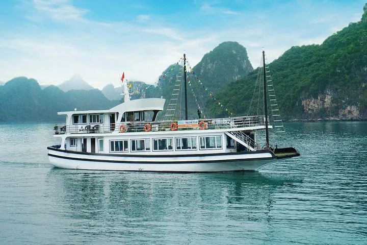 White traditional style cruise boat cruising on the water near mountains